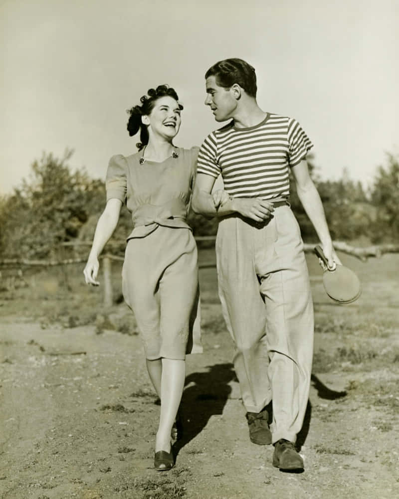 1940s Couple Walkingin Classic Attire Wallpaper