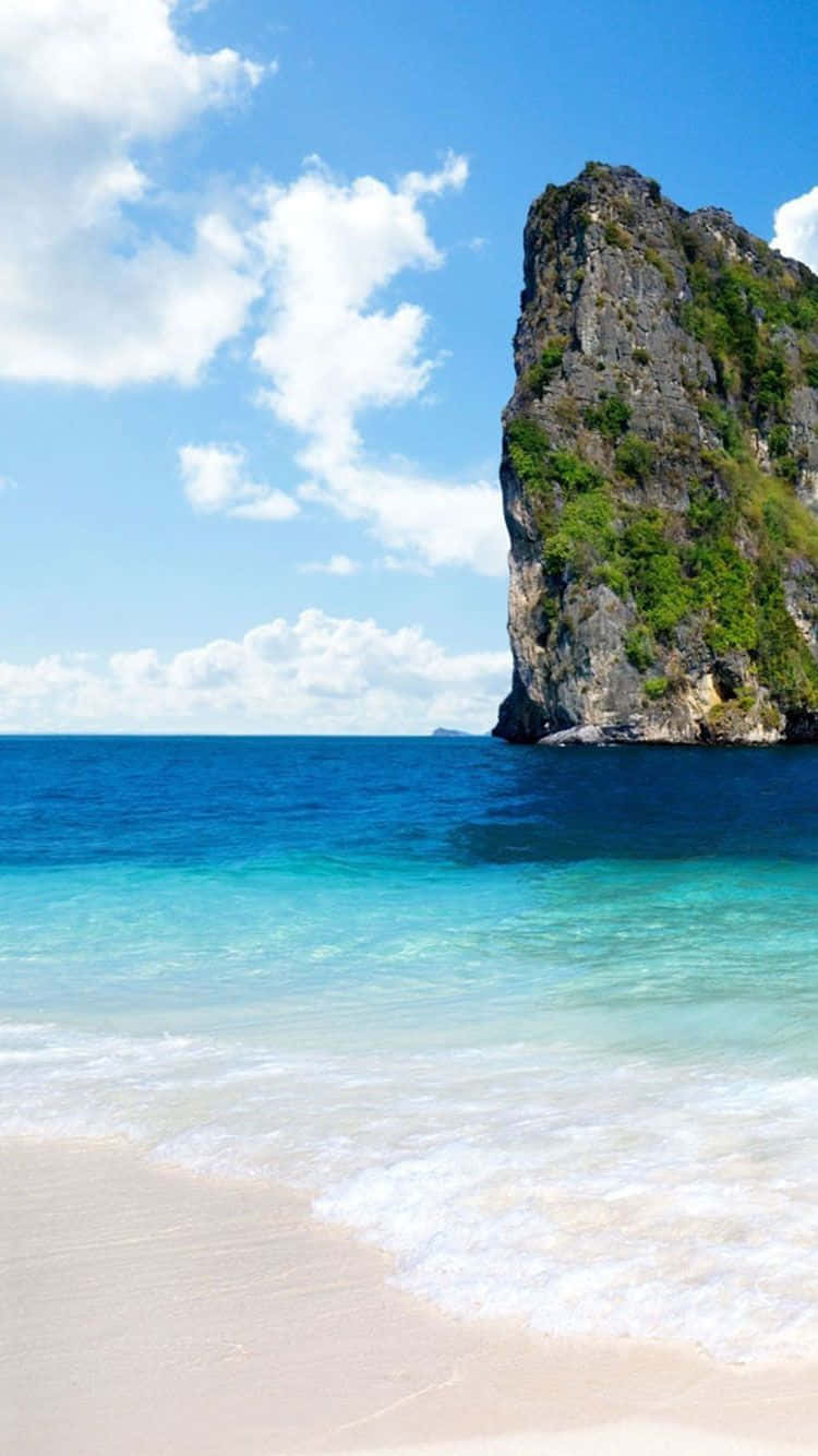 A Beach With A Rocky Cliff In The Water Wallpaper