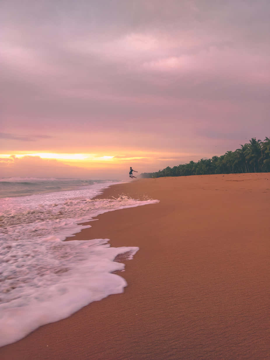 A Beach With Waves And A Sunset Wallpaper