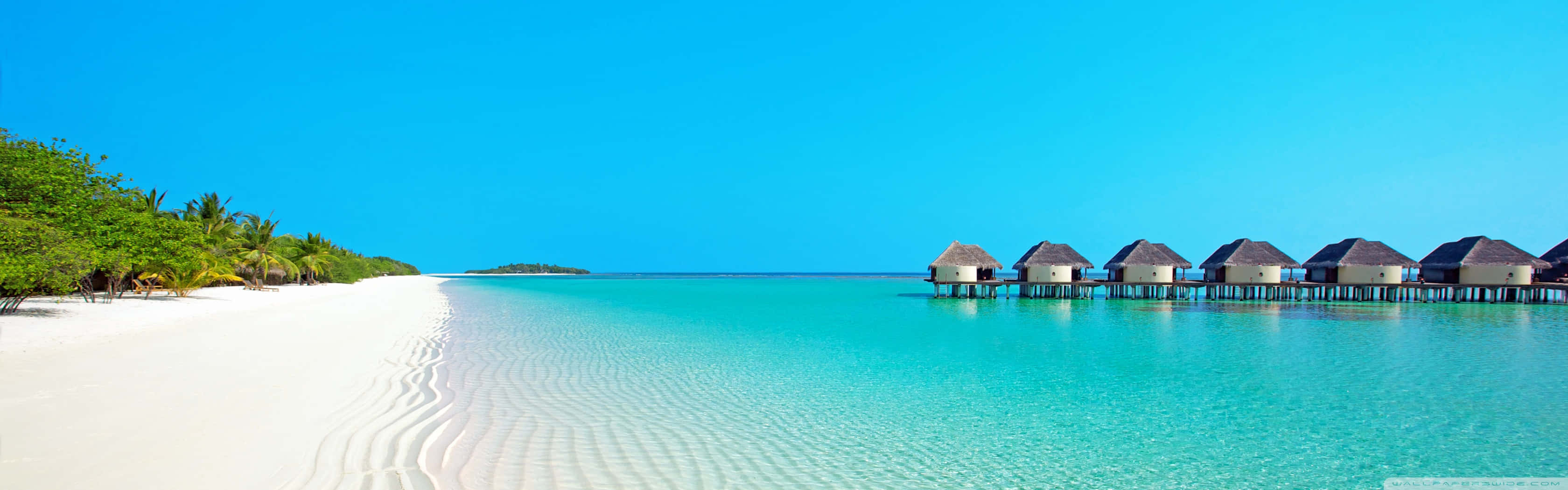 A Beach With White Huts And Clear Water Wallpaper