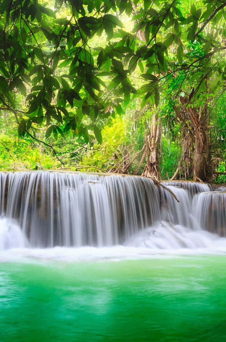 A Beautiful Waterfall Cascades Over Rocks In A Peaceful Setting Wallpaper