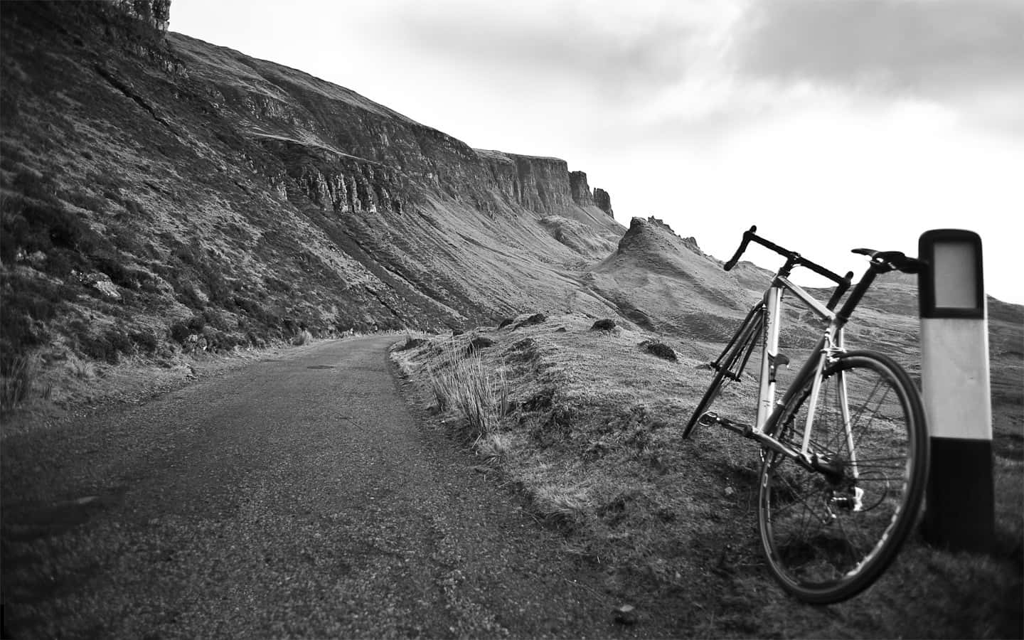 A Bicycle Leaning Against A Pole On A Mountain Road Wallpaper