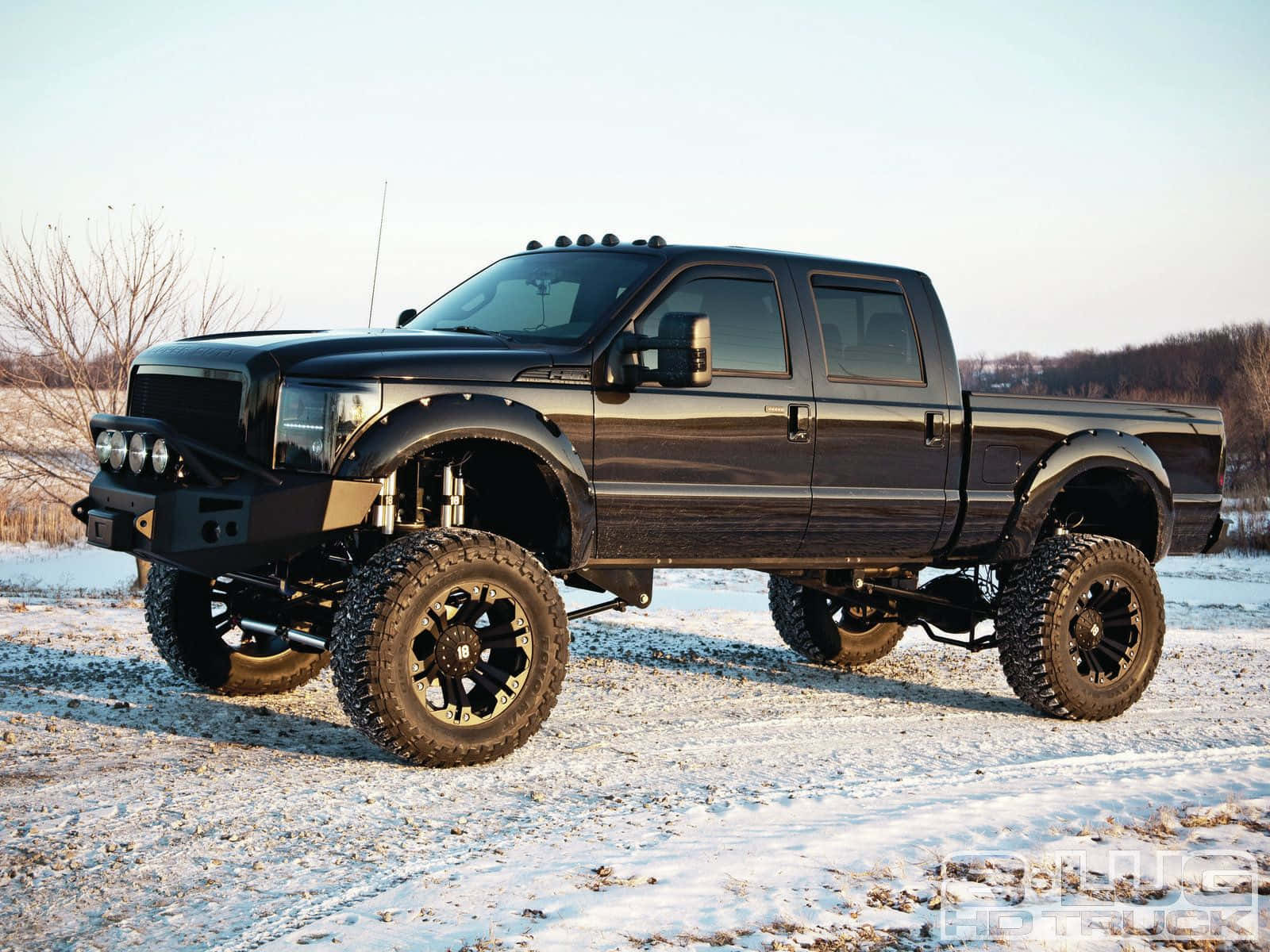 A Black Truck Is Parked In The Snow Wallpaper