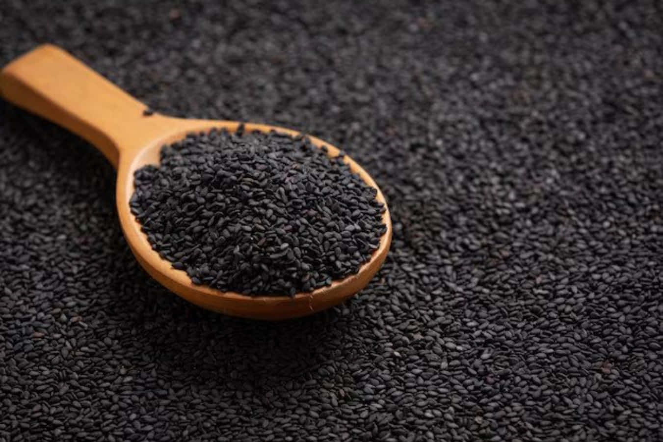 A Bowl Of Black Sesame Seeds, Bathed In A Warm Golden Light Wallpaper