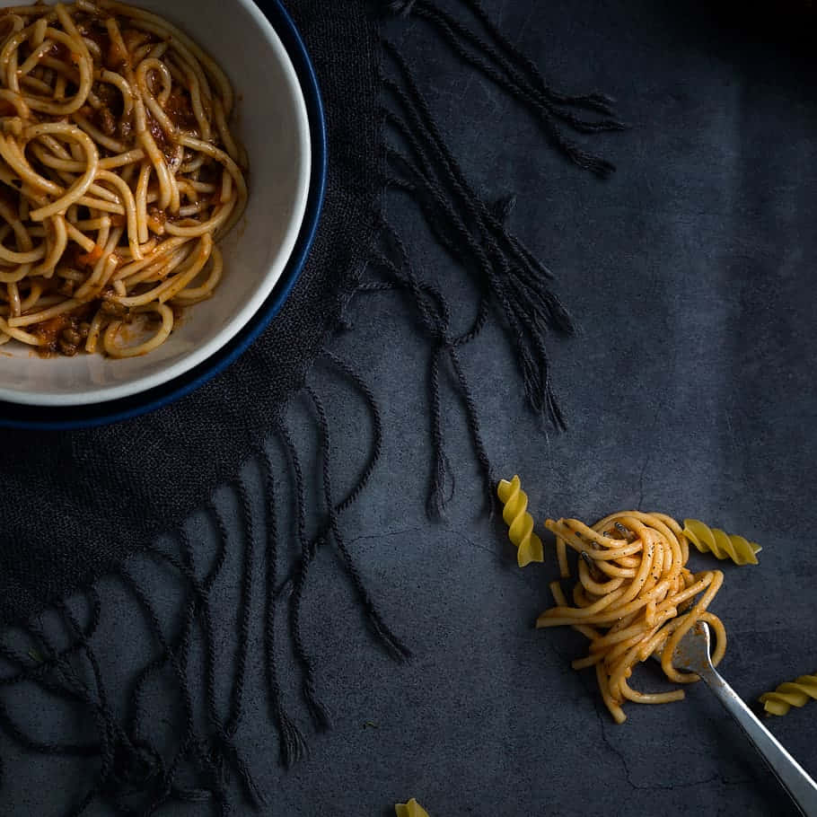 A Bowl Of Spaghetti With Meat Sauce And A Spoon Wallpaper