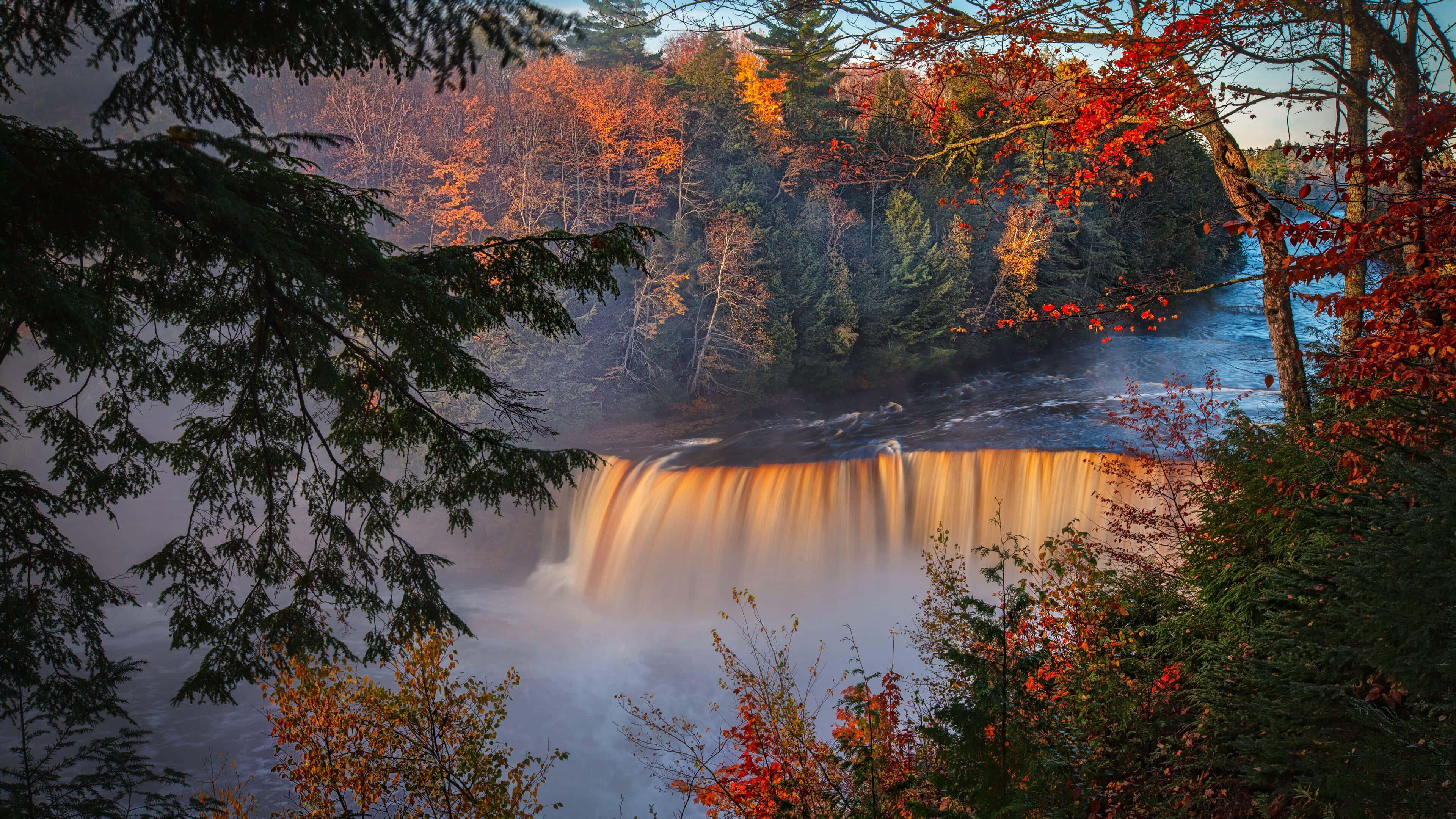 A Breathtaking View Of The 4k Waterfall Amidst Lush Wilderness. Wallpaper