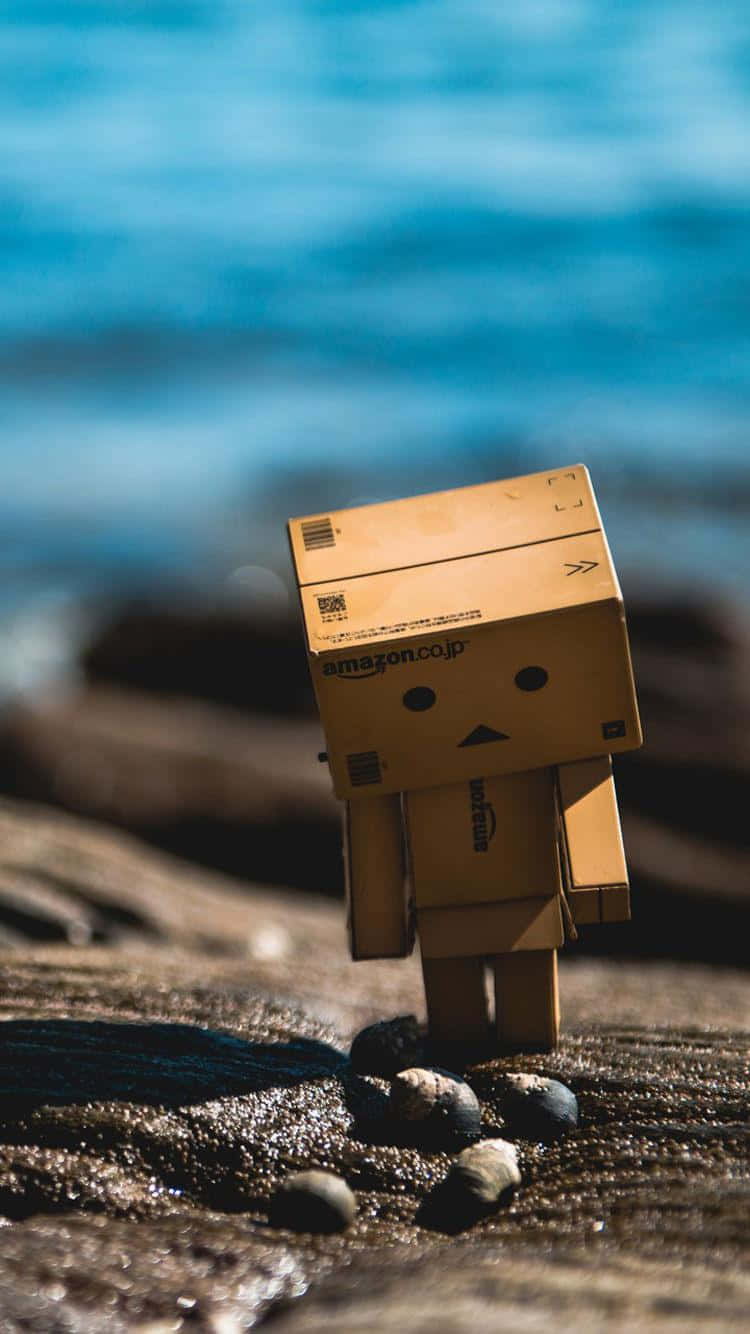 A Cardboard Box Sitting On Rocks Near The Ocean Wallpaper