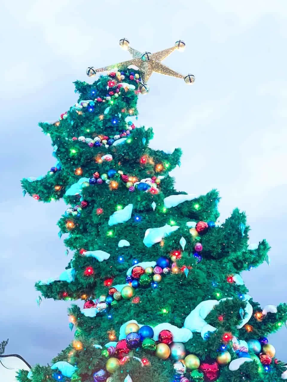 A Christmas Tree With A Lighted Ornament On Top Wallpaper