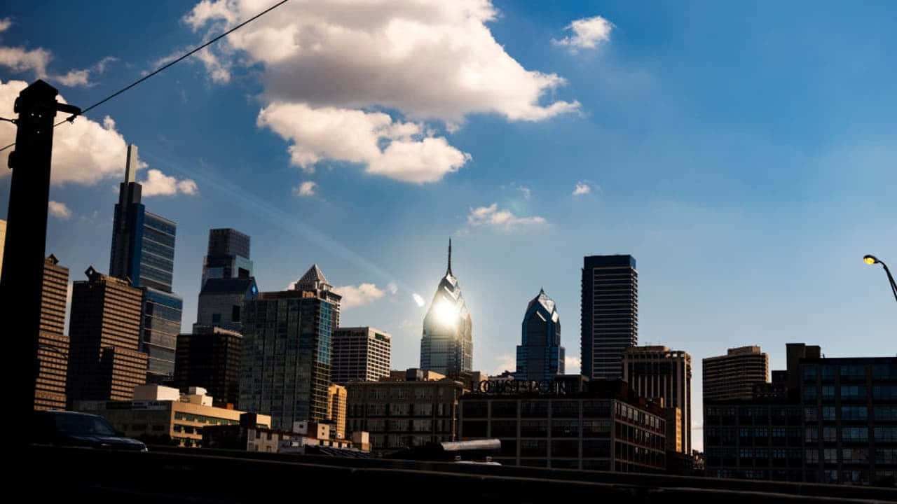 A City Skyline With Clouds And A Bridge Wallpaper