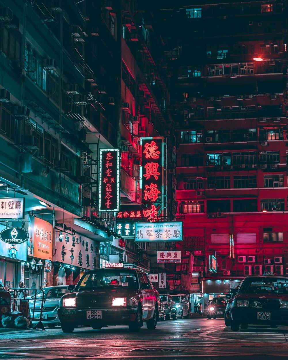 A City Street At Night With Neon Signs Wallpaper