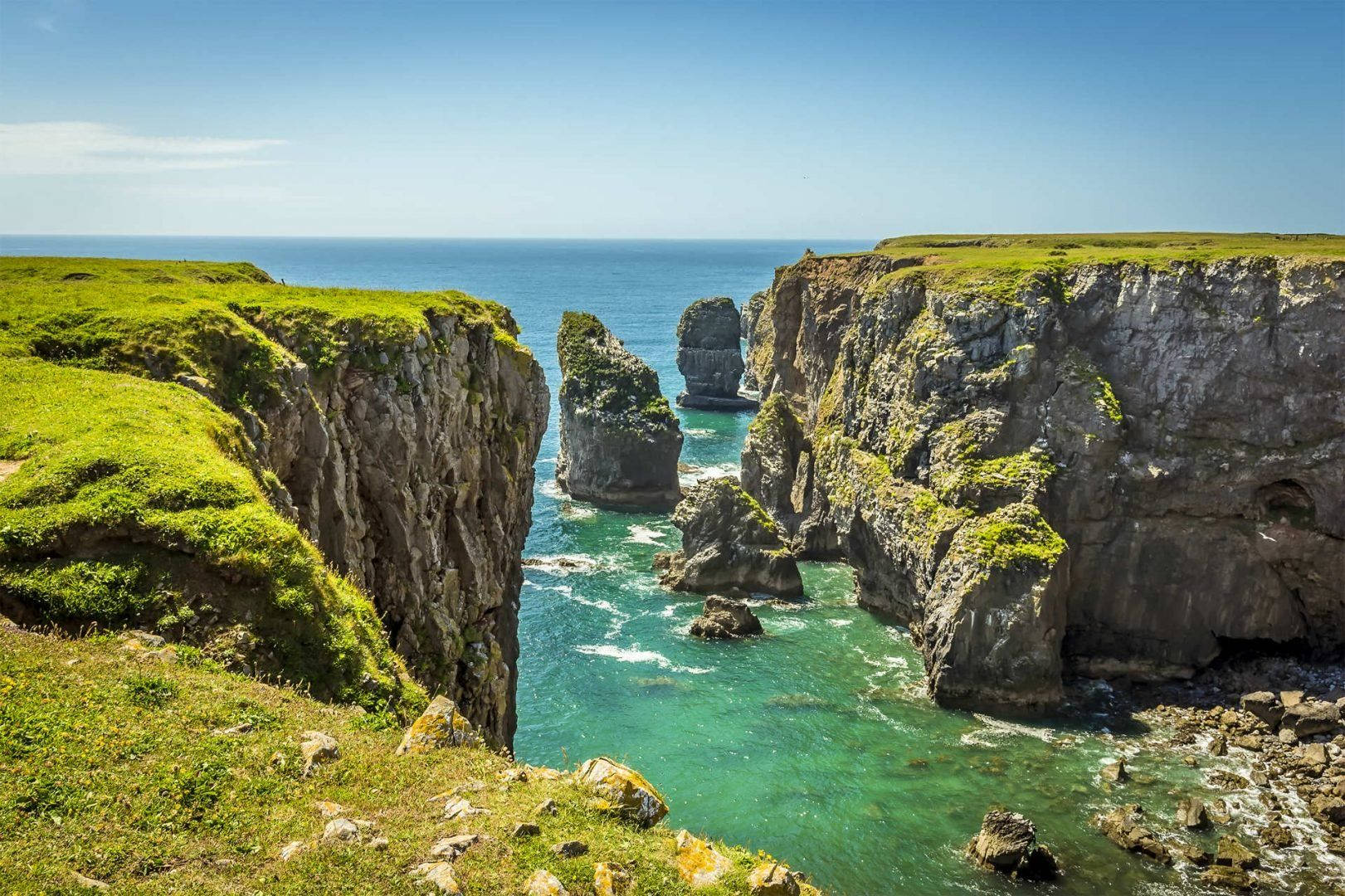 A Cliff With Green Grass And Ocean Wallpaper