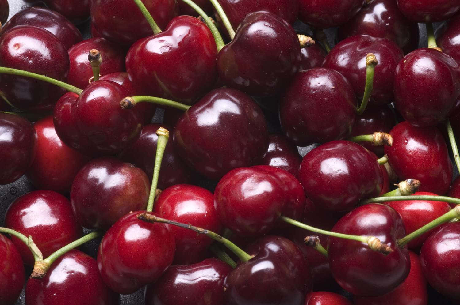 A Close-up Image Of Freshly Picked Red Cherries Wallpaper