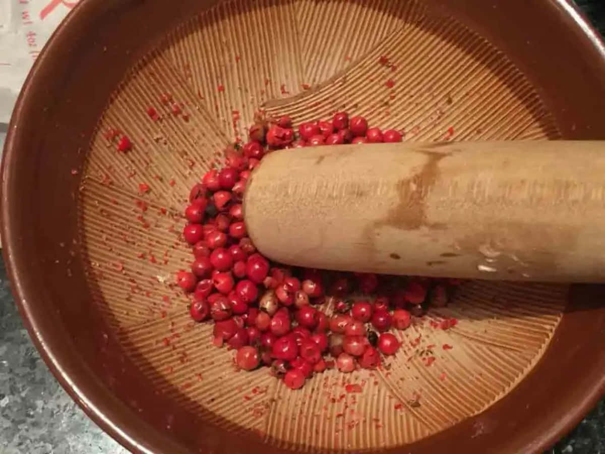 A Close-up View Of Vibrant Pink Peppercorns On A Wooden Surface Wallpaper