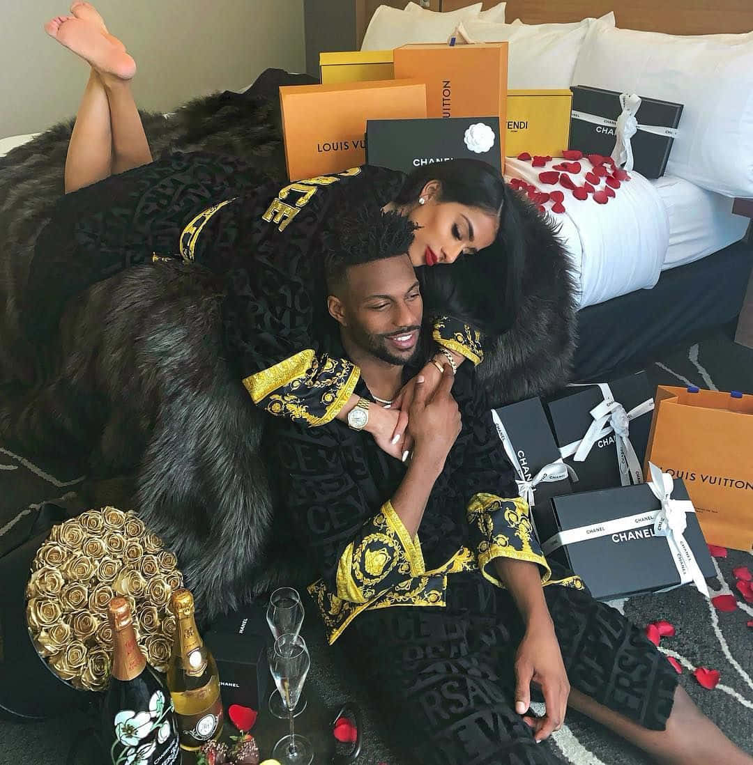 A Couple Laying On A Bed With Gifts On The Bed Wallpaper