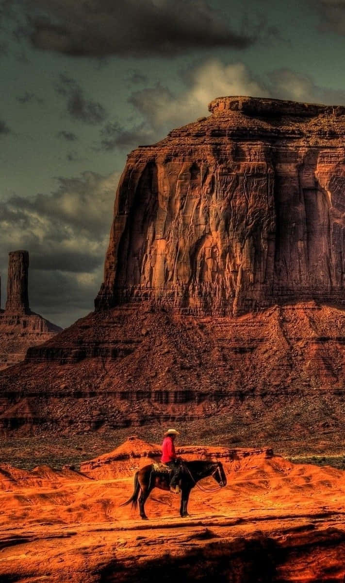 A Cowboy Riding A Horse In Monument Valley Wallpaper