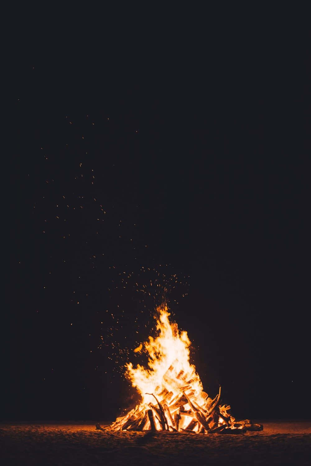 A Cozy Beach Bonfire Under A Starry Sky Wallpaper