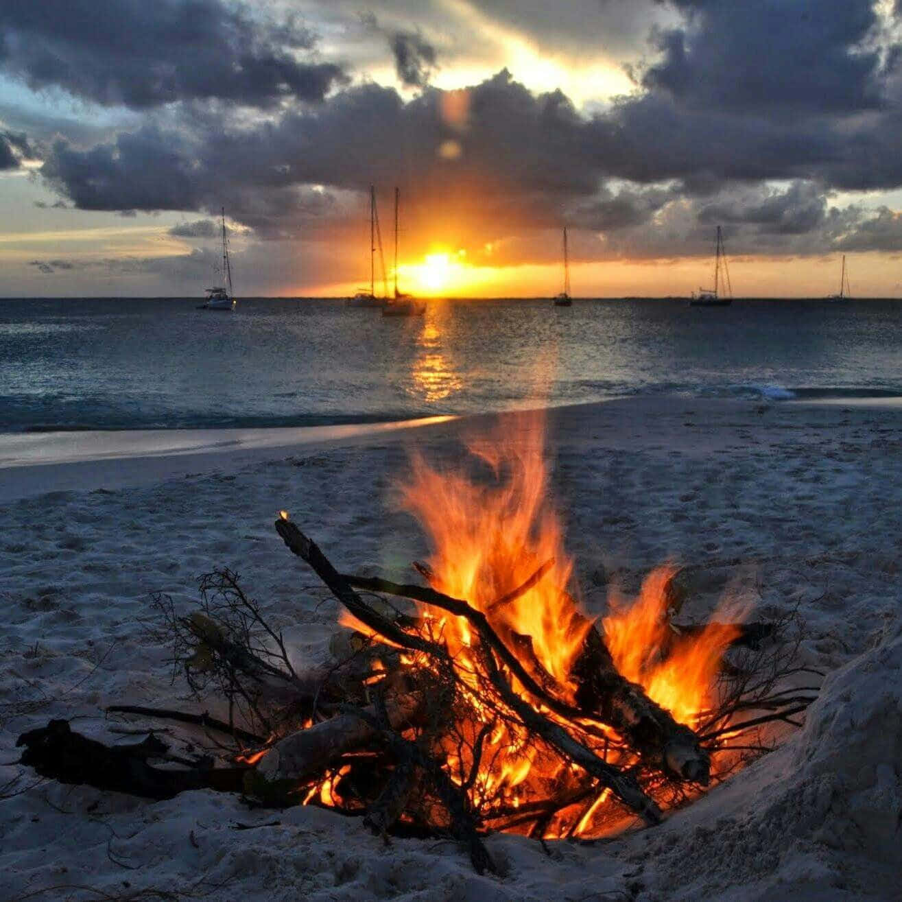 A Cozy Campfire Illuminating A Serene Beach At Night Wallpaper