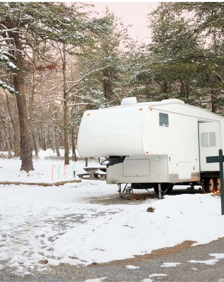 A Cozy Winter Campsite Amidst Serene Snow-covered Mountains Wallpaper