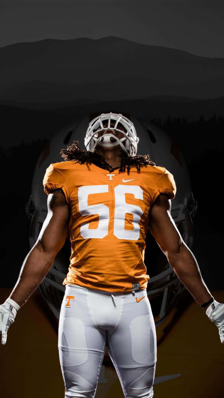 A Football Player In A Uniform Standing In Front Of A Mountain Wallpaper