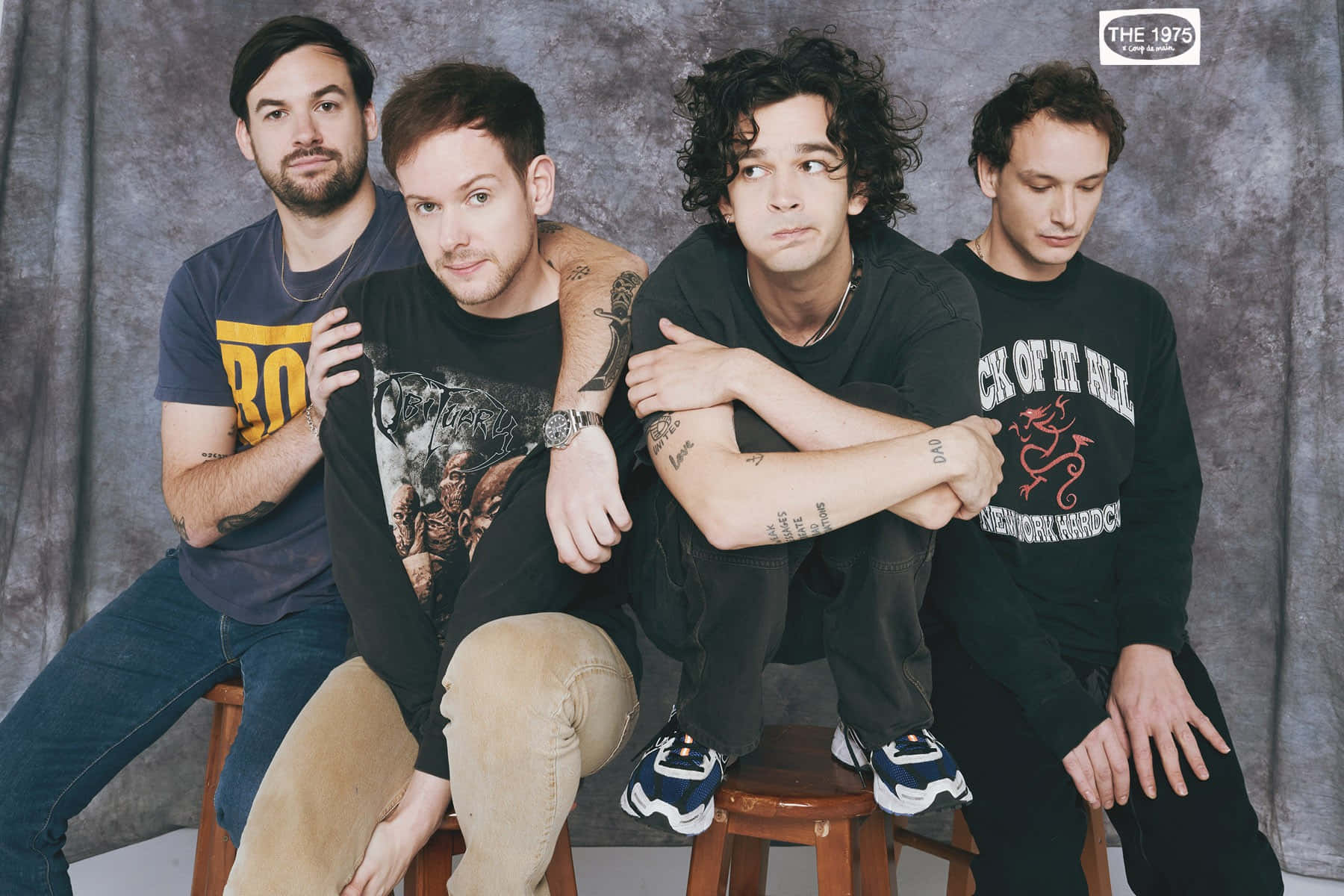 A Group Of Men Sitting On Stools Wallpaper