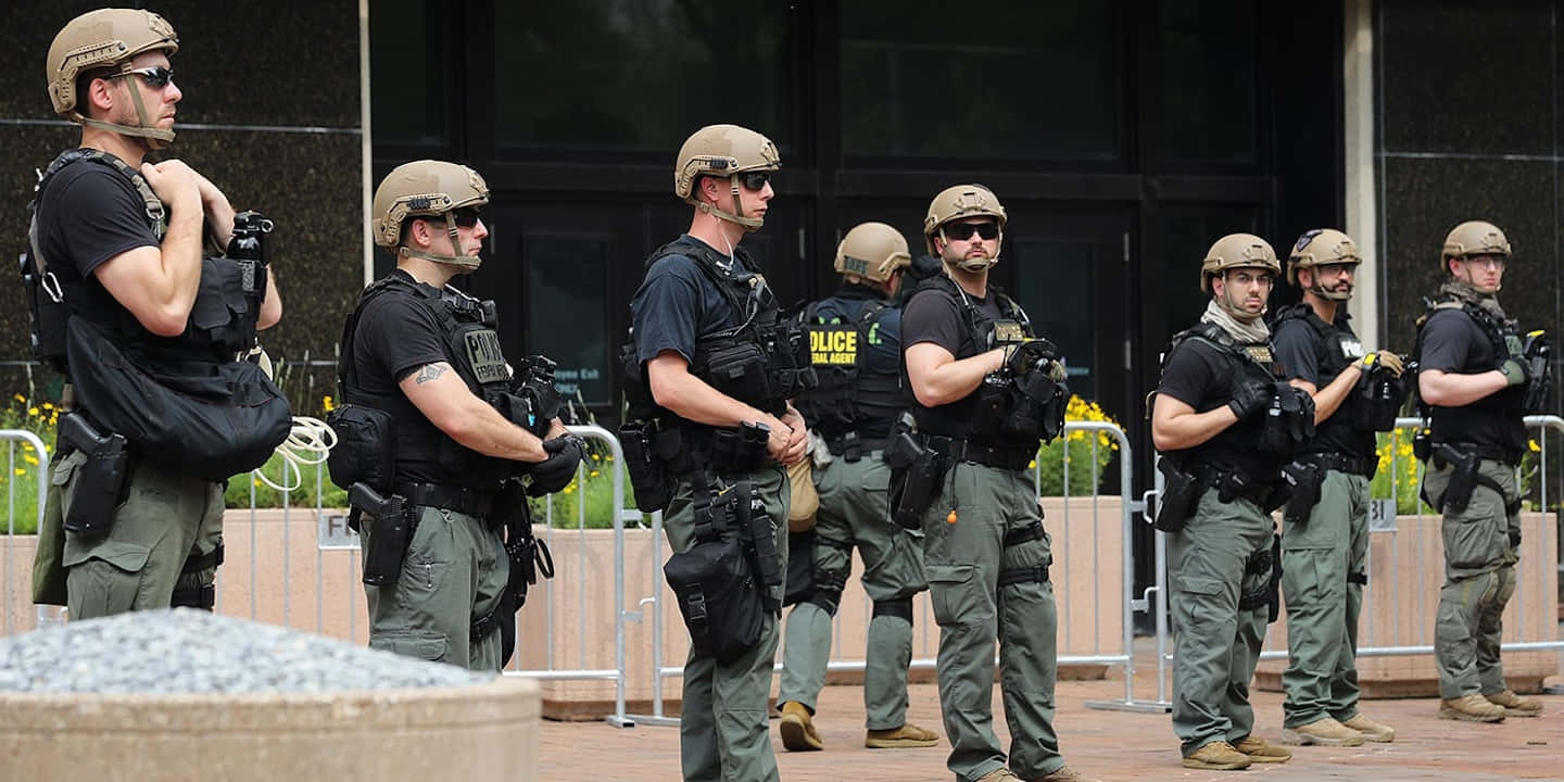 A Group Of Police Officers Standing Outside Of A Building Wallpaper