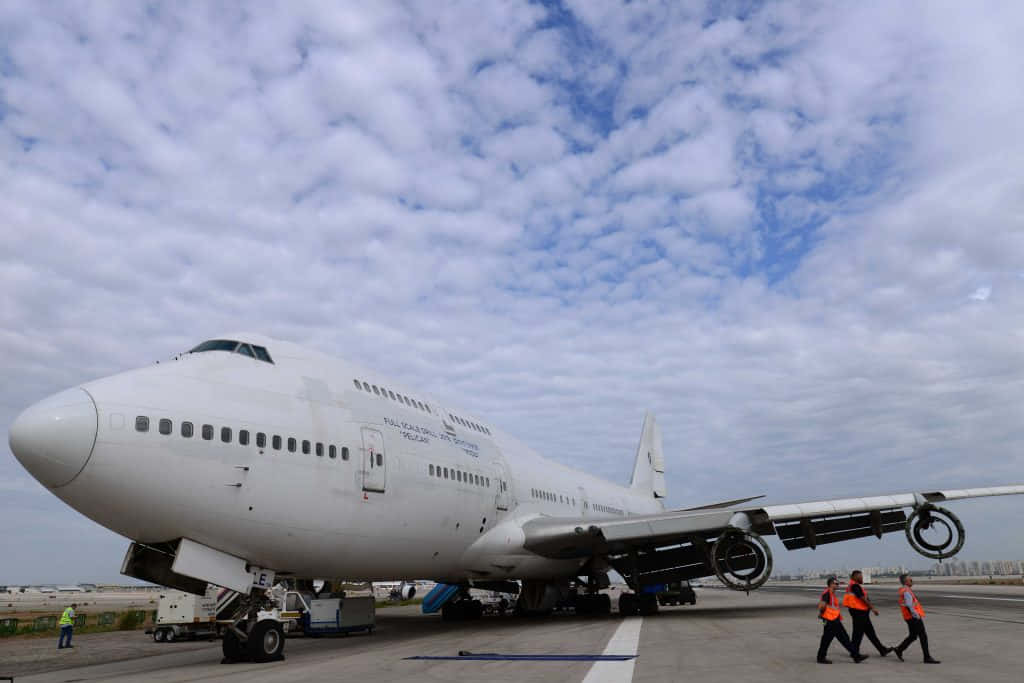 A Large Airplane On The Tarmac With People Walking Around It Wallpaper