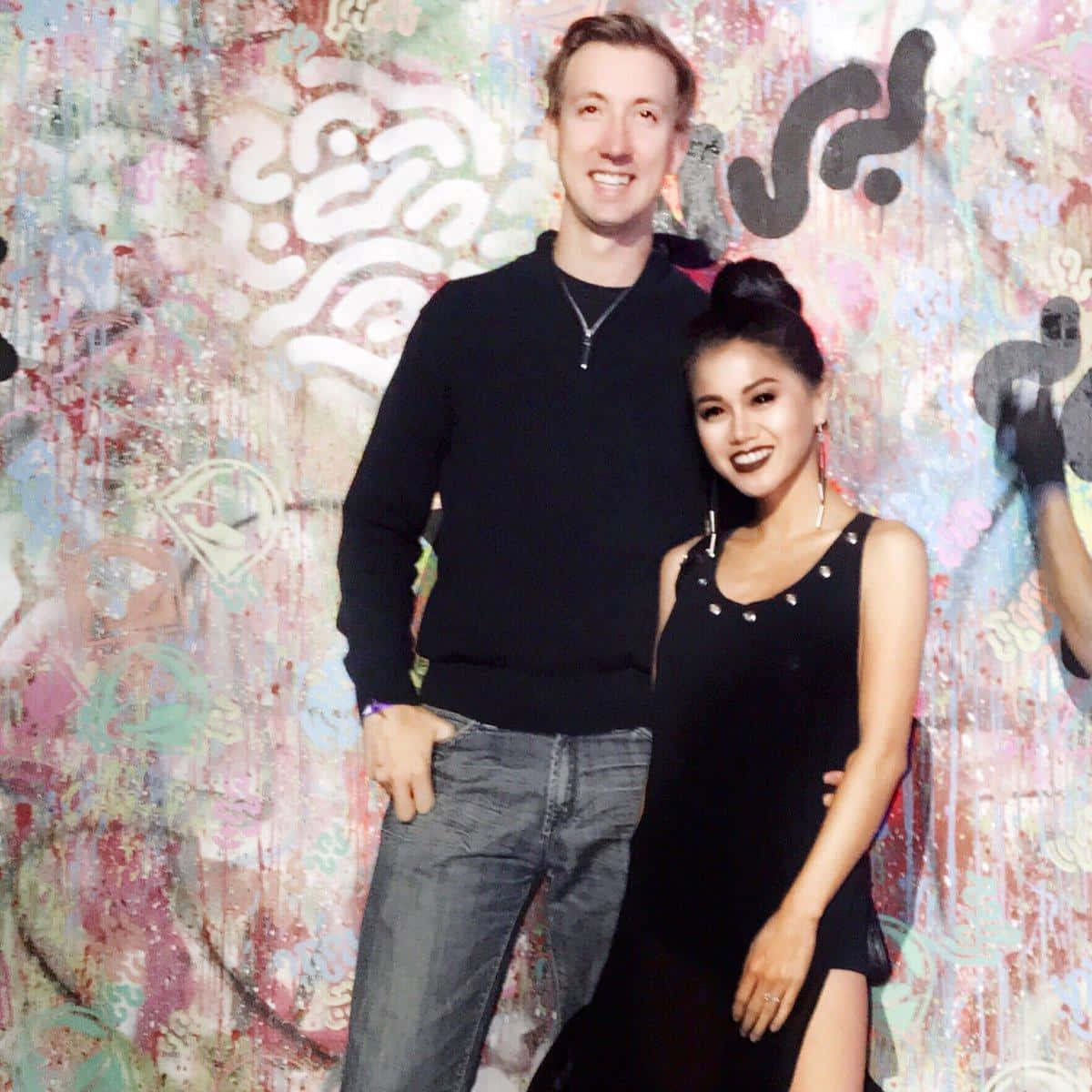 A Man And Woman Standing In Front Of A Wall Wallpaper