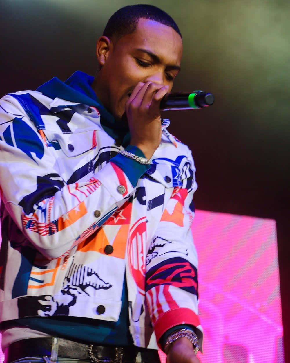 A Man In A Colorful Jacket Singing Into A Microphone Wallpaper