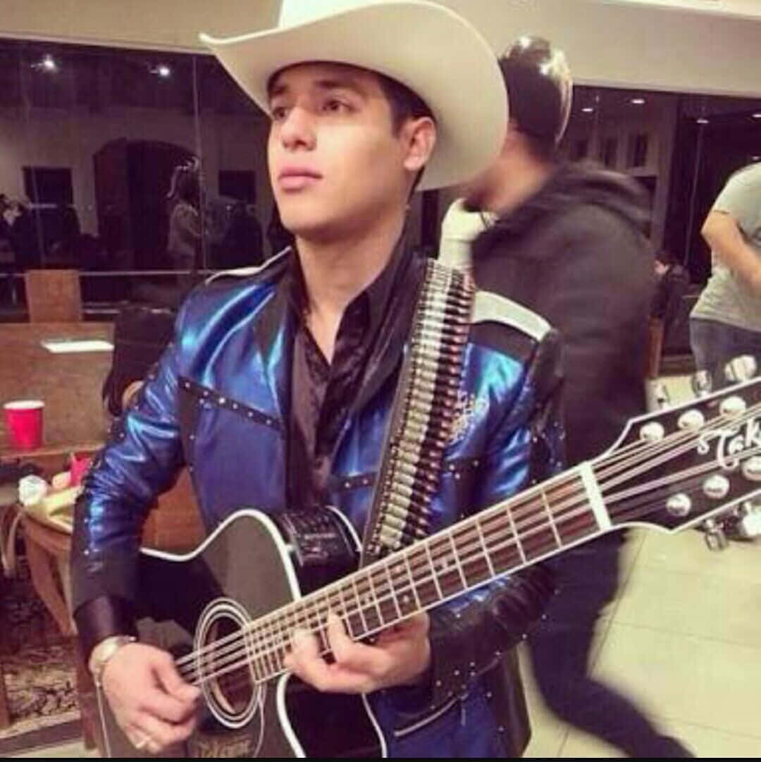 A Man In A Cowboy Hat Holding A Guitar Wallpaper