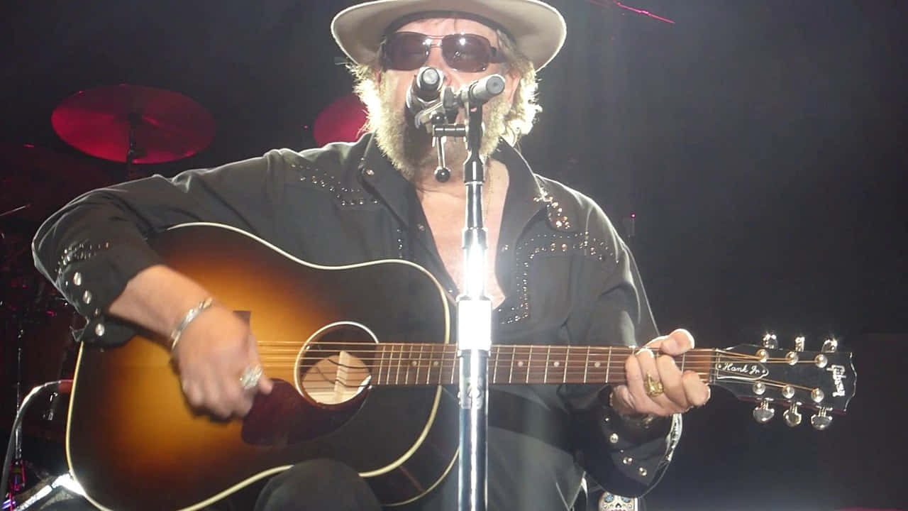 A Man In A Hat And Sunglasses Playing An Acoustic Guitar Wallpaper