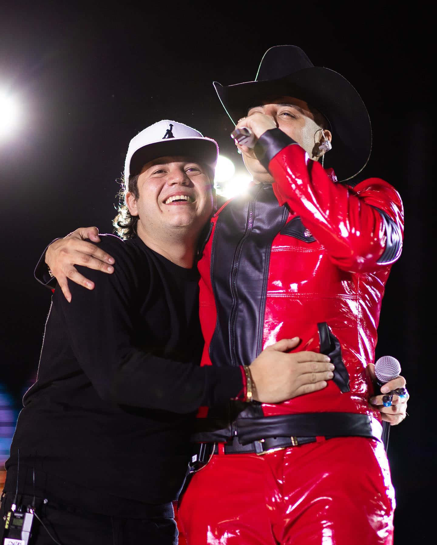 A Man In A Red Jacket And Hat Is Hugging Another Man Wallpaper