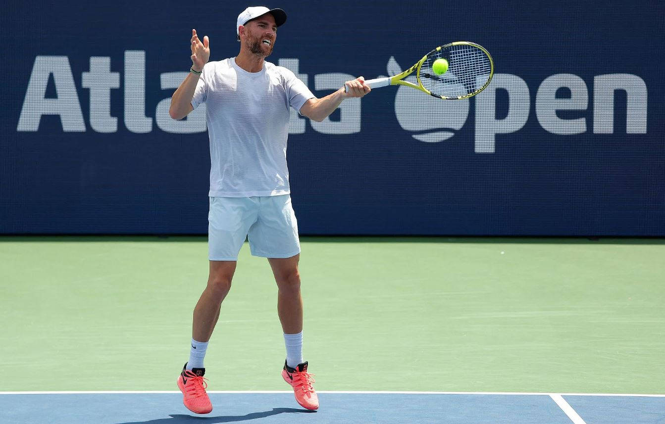 A Man Is Playing Tennis On A Tennis Court Wallpaper