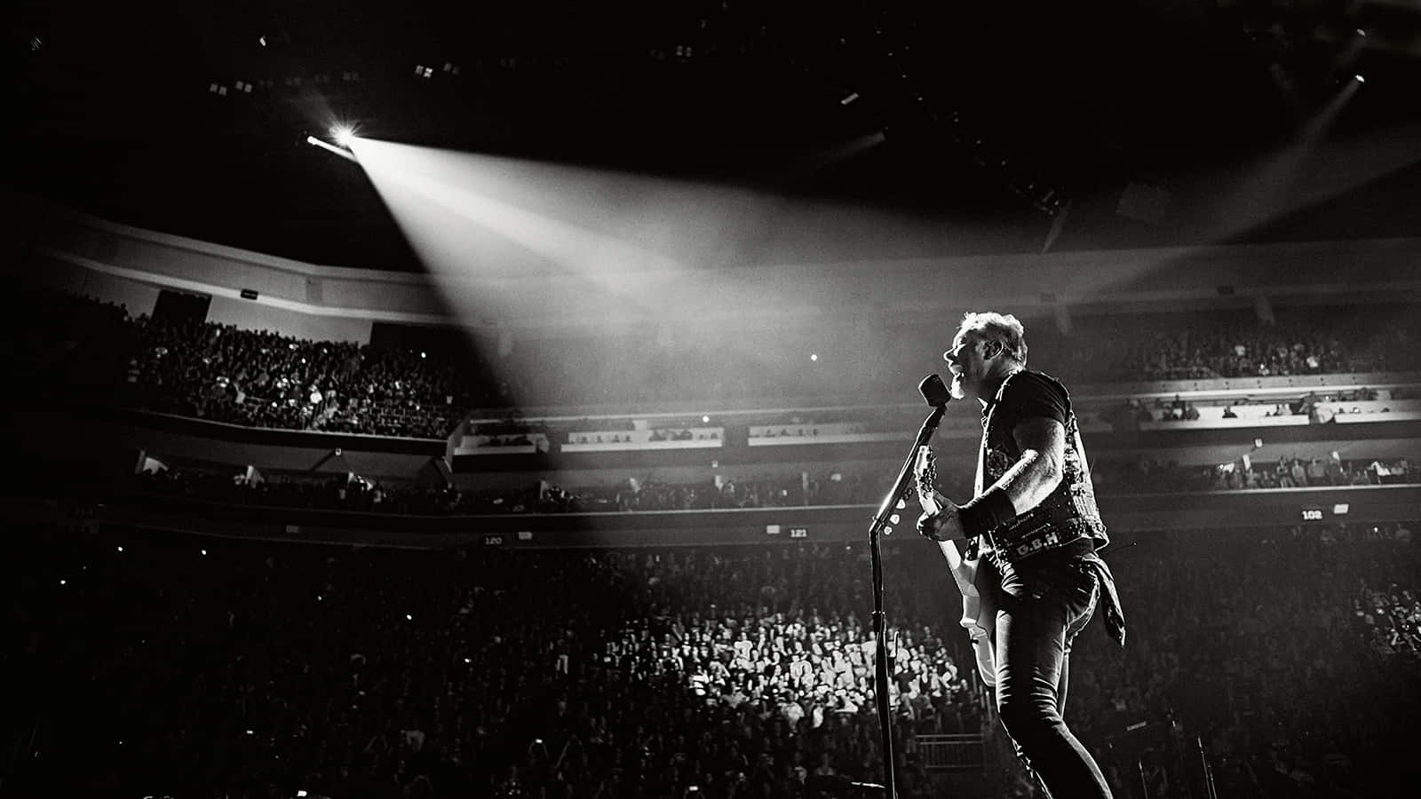 A Man Is Standing On Stage In Front Of A Spotlight Wallpaper