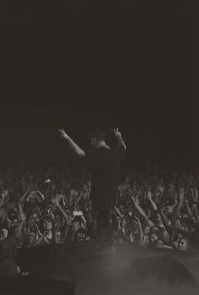 A Man Is Standing On Stage With His Arms Raised Wallpaper