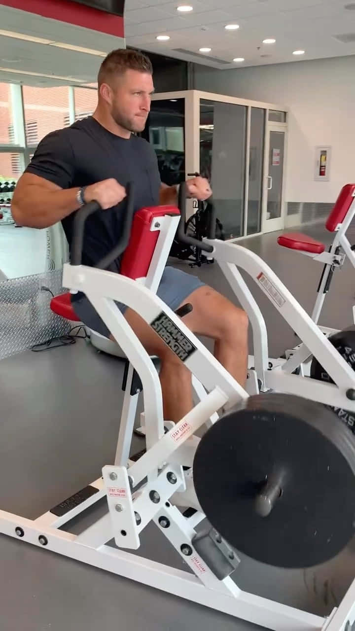 A Man Is Using A Rowing Machine In A Gym Wallpaper