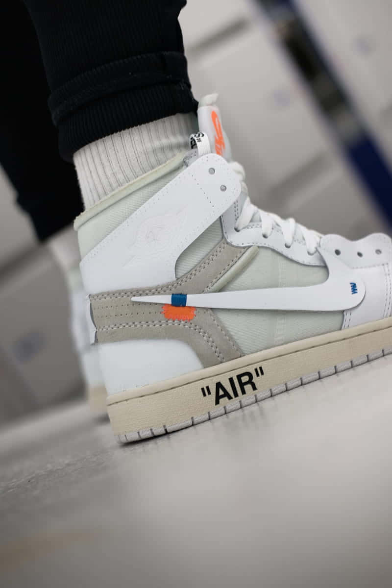 A Man Is Wearing A White - Off - White - Air Jordan 1 Mid Wallpaper