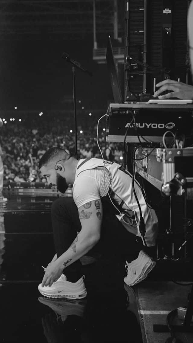 A Man Kneeling On The Floor While A Man Is Playing A Keyboard Wallpaper