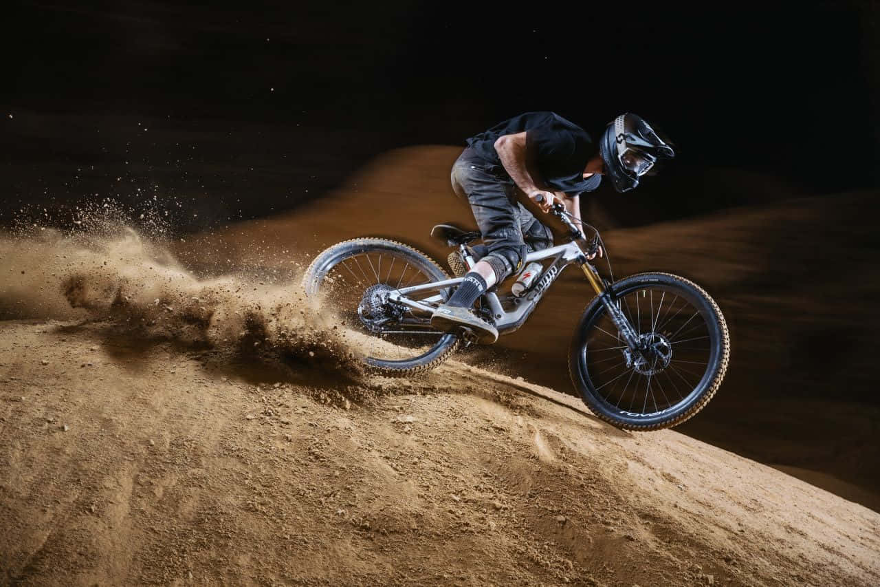 A Man Riding A Mountain Bike On A Dirt Hill Wallpaper