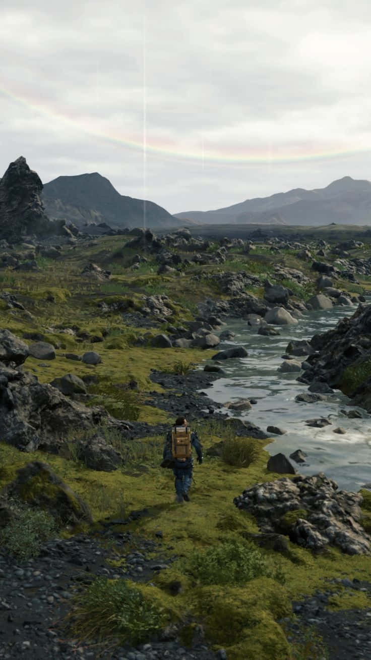 A Man Walking Through A Grassy Area With A Rainbow Wallpaper