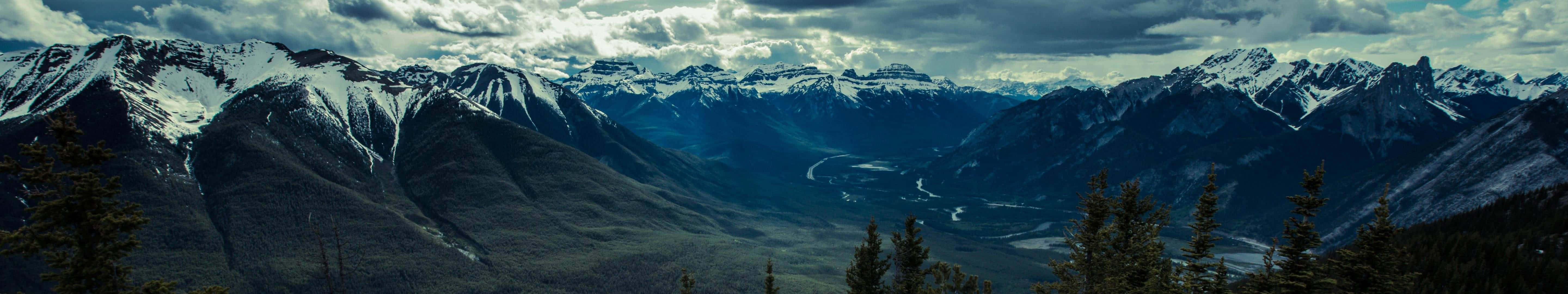 A Mountain Range With Clouds And Snow Wallpaper