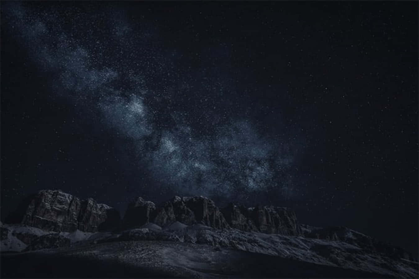 A Mountain Range With Snow And Stars In The Sky Wallpaper