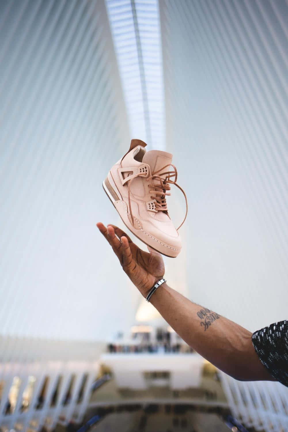 A Person Holding A Pink Shoe In Front Of A Building Wallpaper