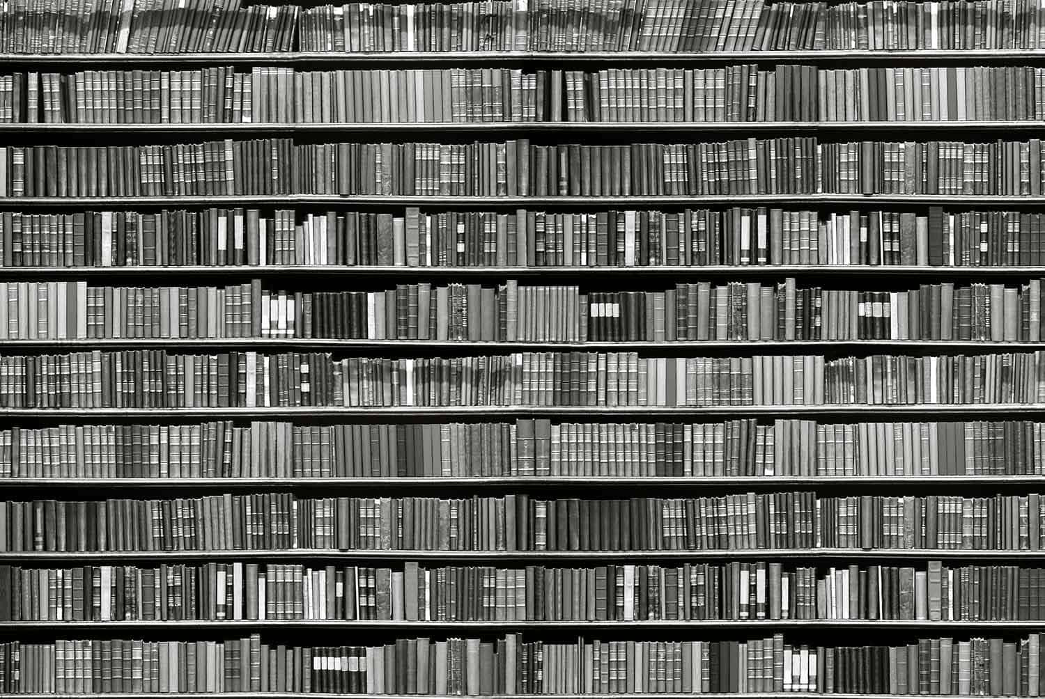 A Person Reading An Open Book Resting On A Table In Black And White Wallpaper