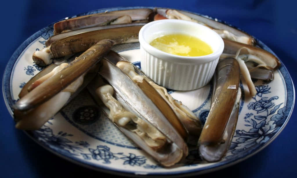 A Pristine Razor Clam Emerging From The Sand At The Beach Wallpaper