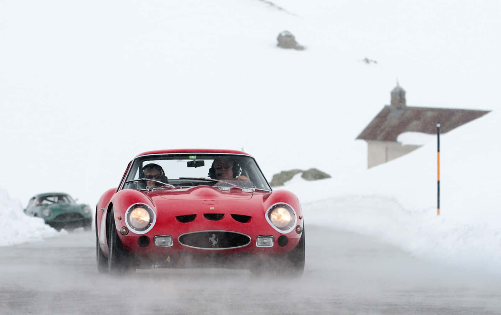 A Red Sports Car Driving Down A Snowy Road Wallpaper