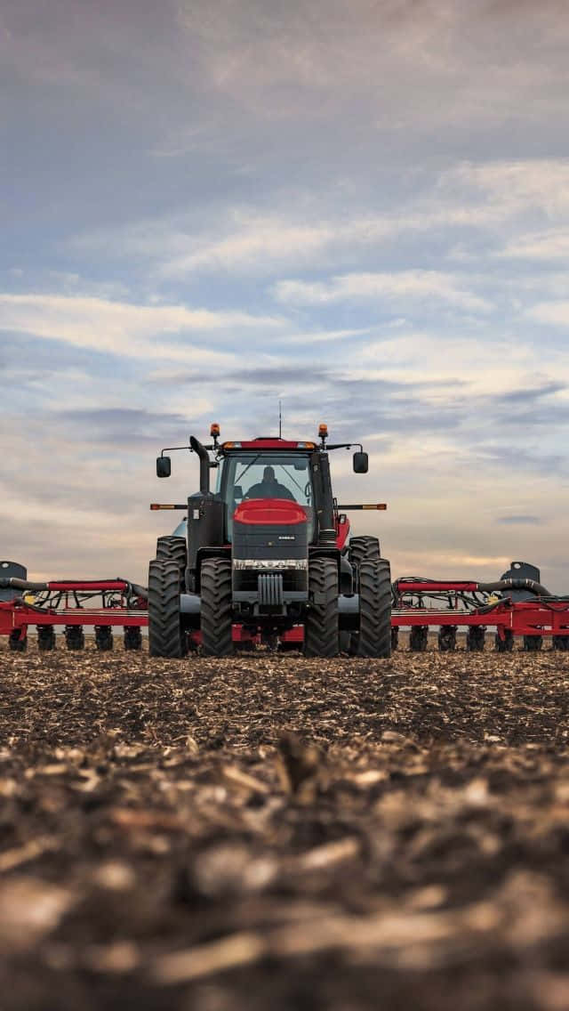 A Red Tractor Is Parked In A Field Wallpaper