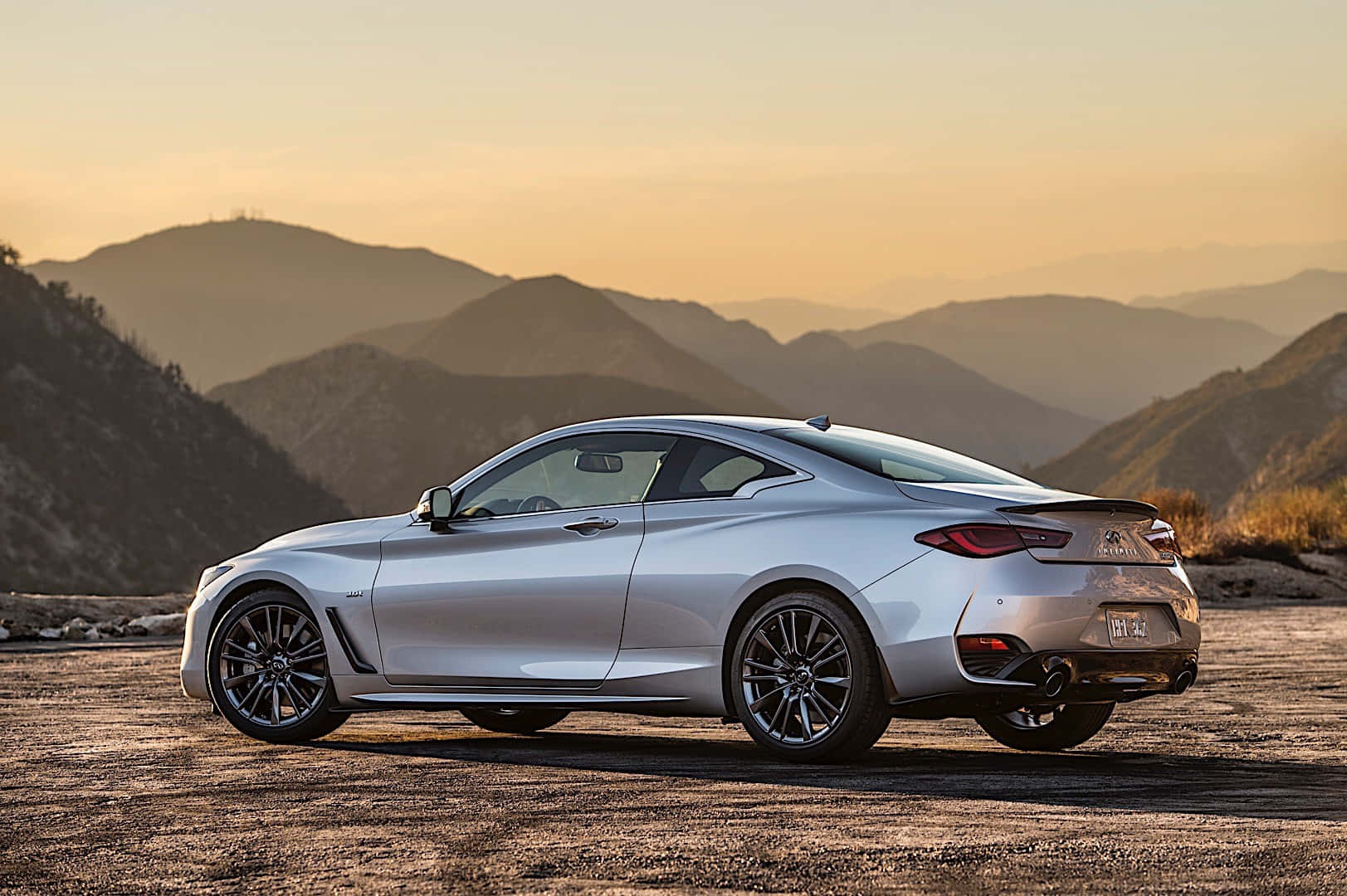 A Sleek Silver Infiniti Q60 Parked Near A Harbor Wallpaper