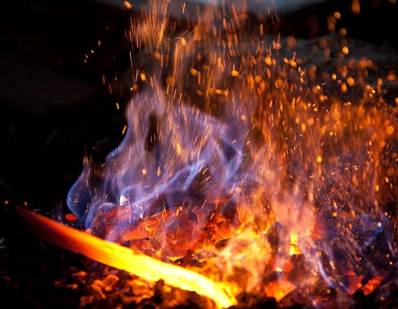 A Smart Blacksmith Stands Over A Blazing Forge And Hard At Work. Wallpaper