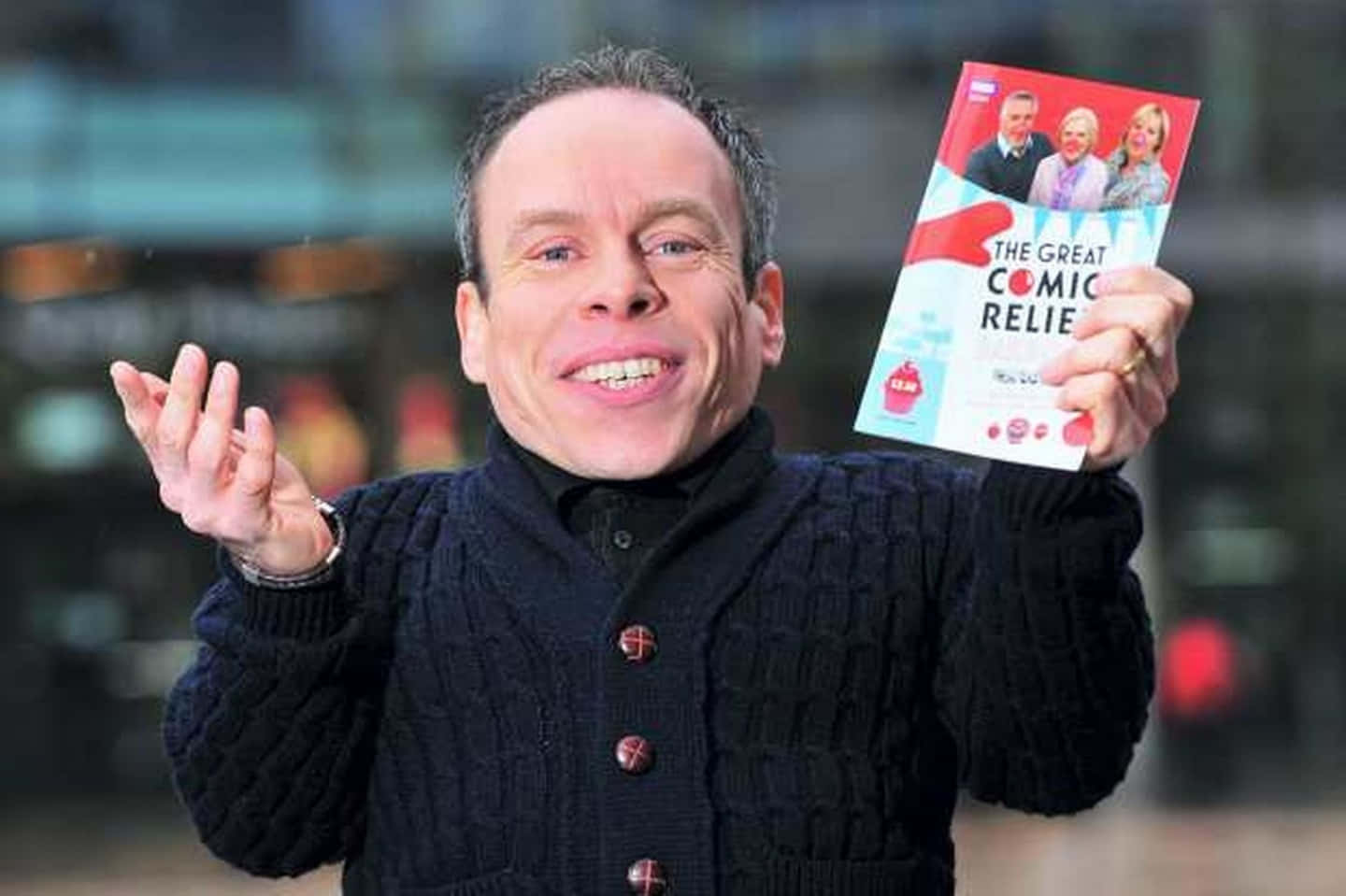 A Smiling Warwick Davis Posing For A Portrait Wallpaper