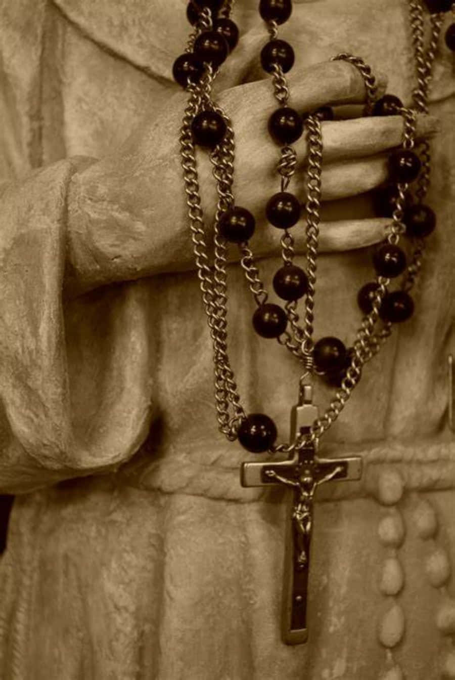 A Statue Of A Man Holding A Rosary Wallpaper